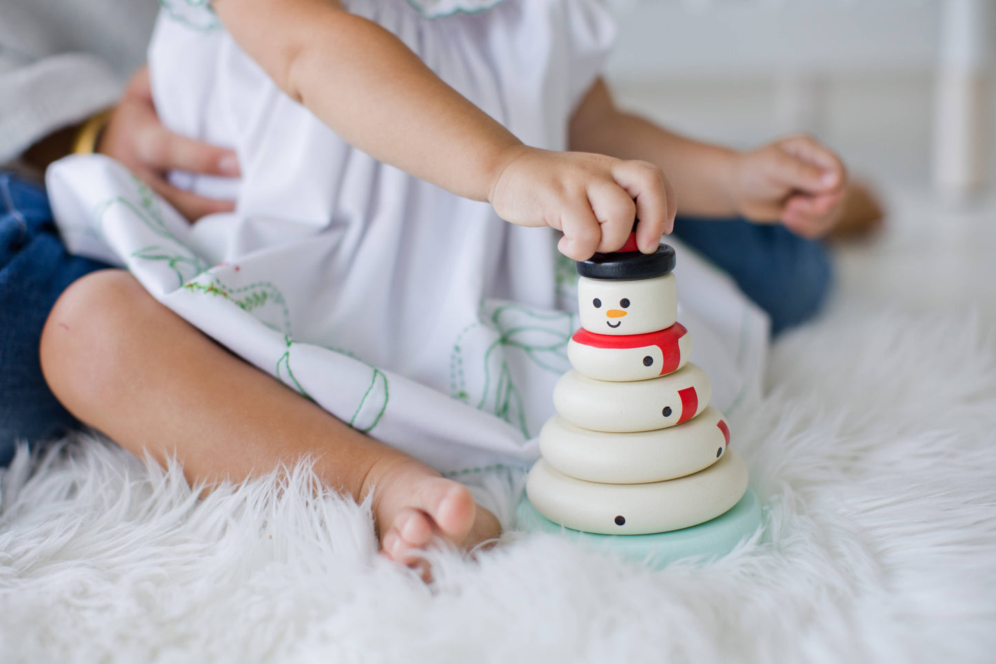 Baby playing with Wooden Snowman Stacking Holiday Toy, practicing hand-eye coordination and stacking skills