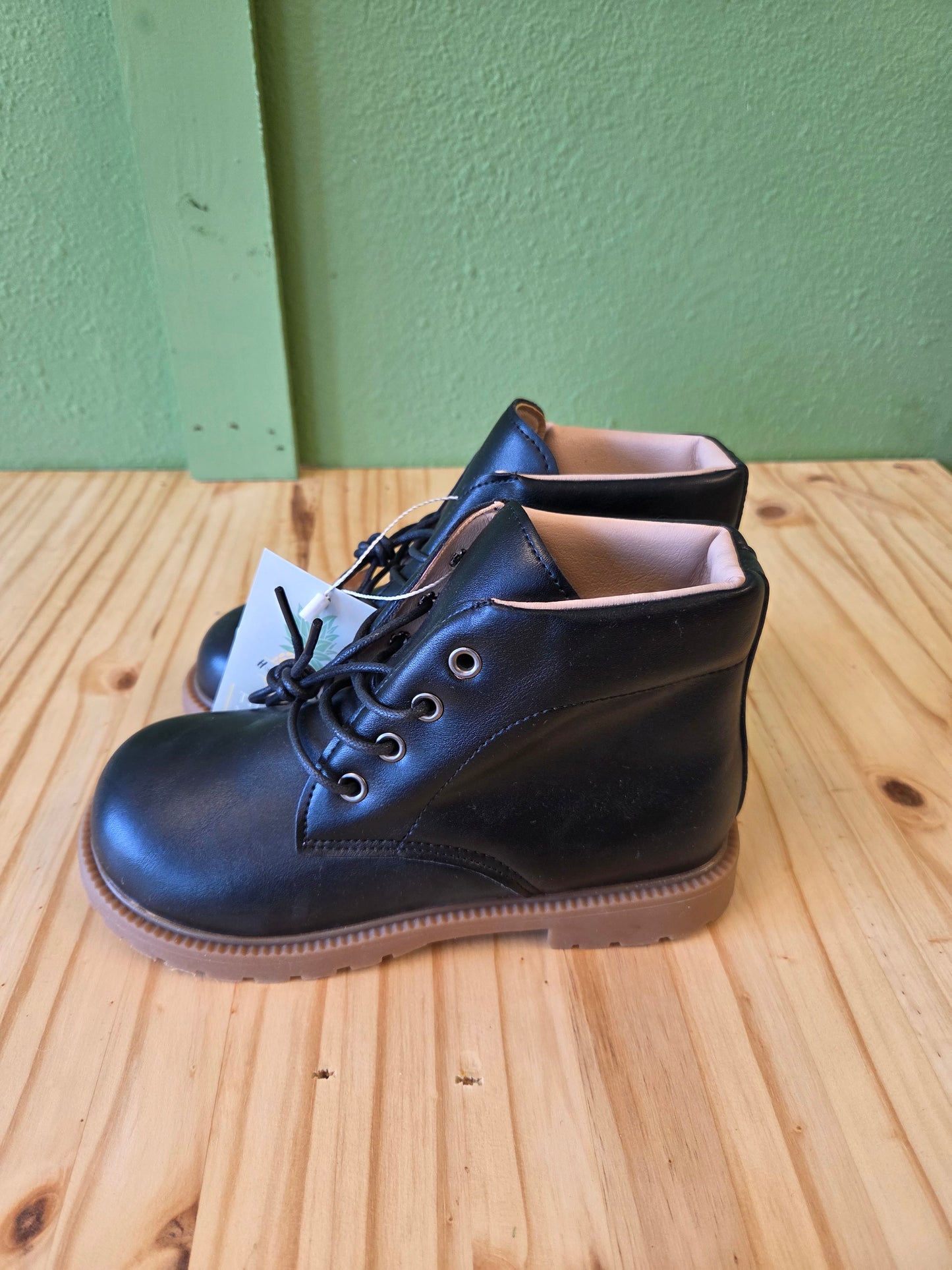 Side view of black unisex toddler and youth combat boots, highlighting silhouette and lace-up detail