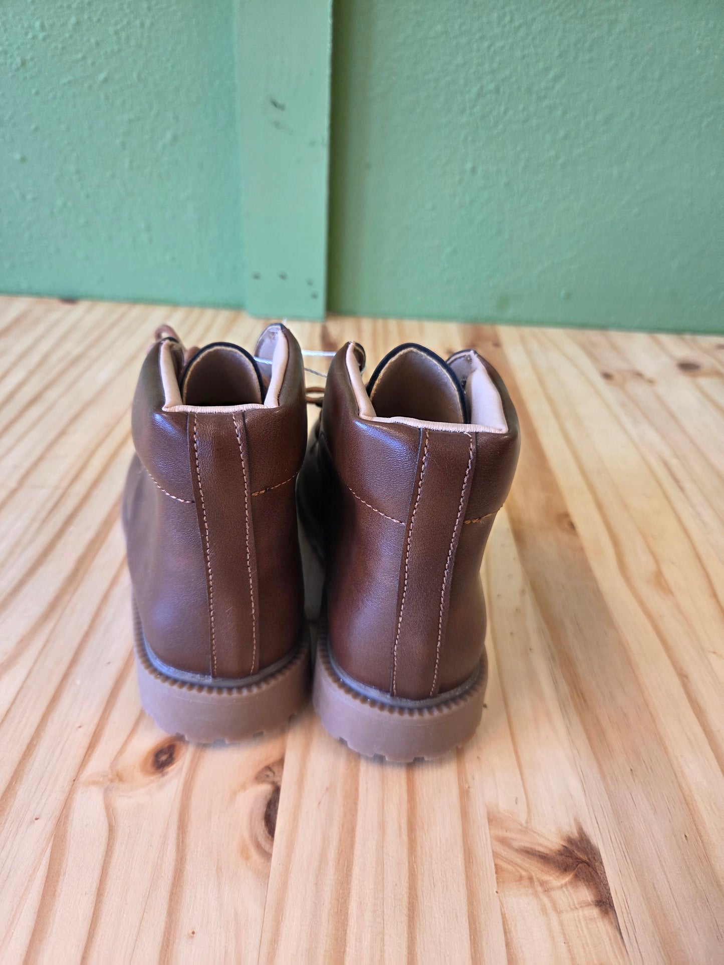 Back view of brown unisex toddler and youth combat boots, highlighting heel, stitching, and overall construction