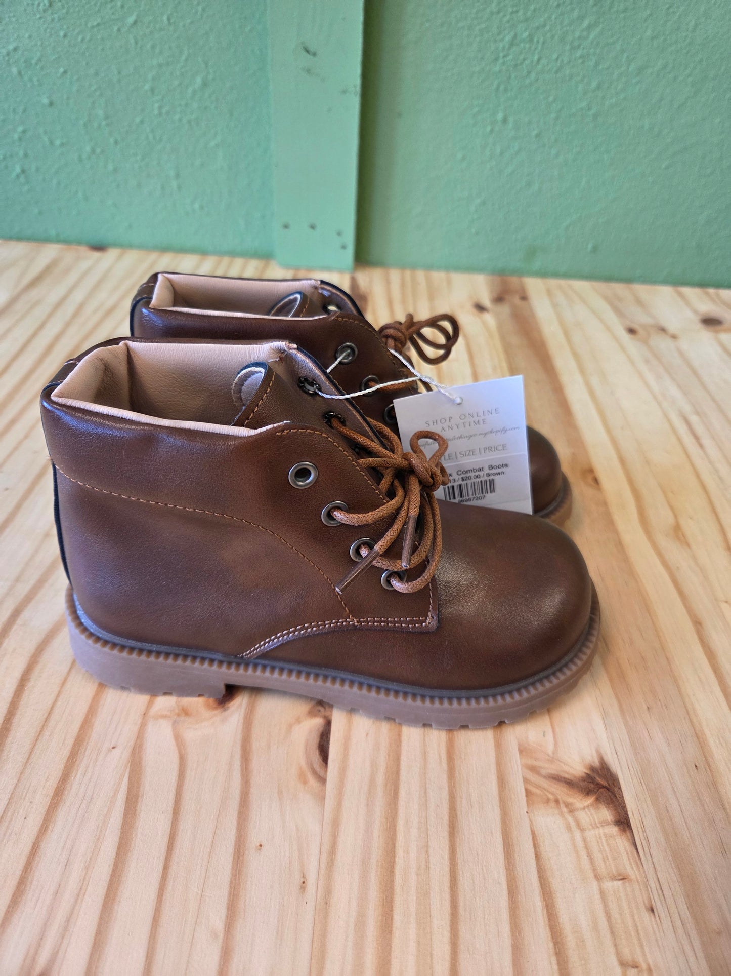 Side view of brown unisex toddler and youth combat boots, showing silhouette and lace-up detail
