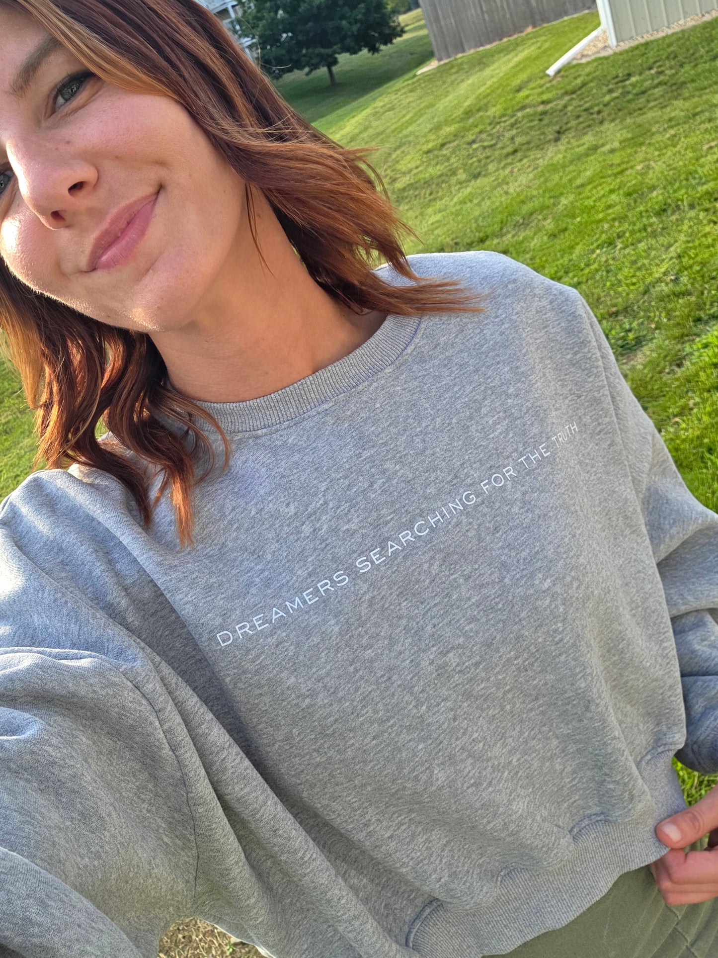 Close front view selfie of woman wearing Dreamers Searching for the Truth oversized crop crewneck, promoting infertility awareness
