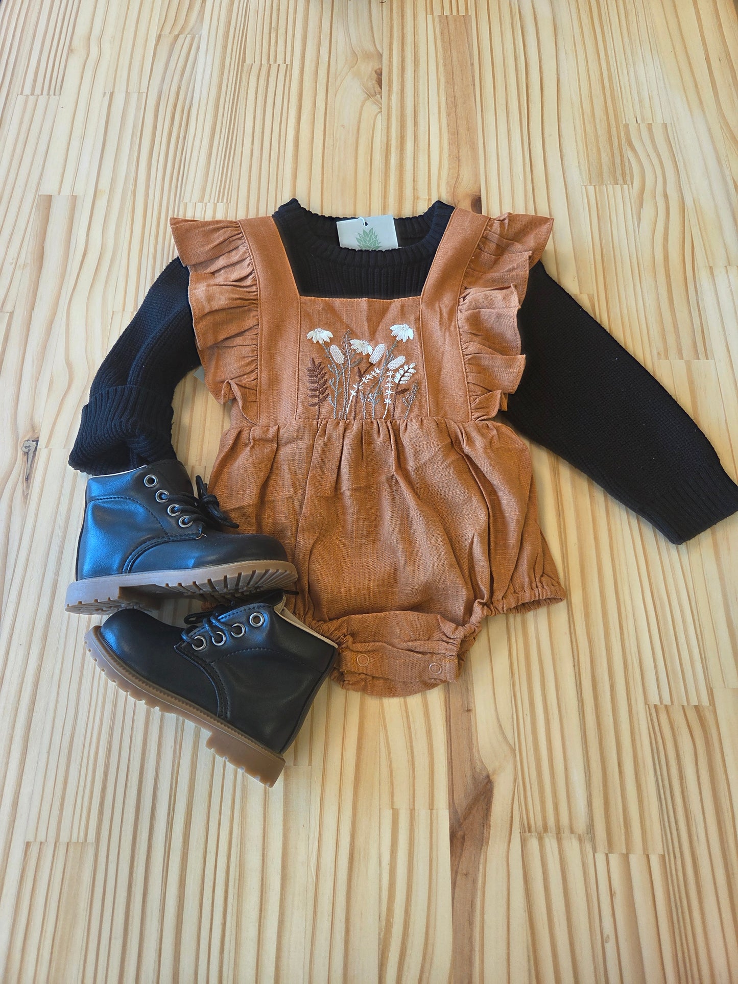 Eleanor Embroidered Romper styled with sweater and boots, full outfit view, showing caramel linen, floral embroidery, and ruffles