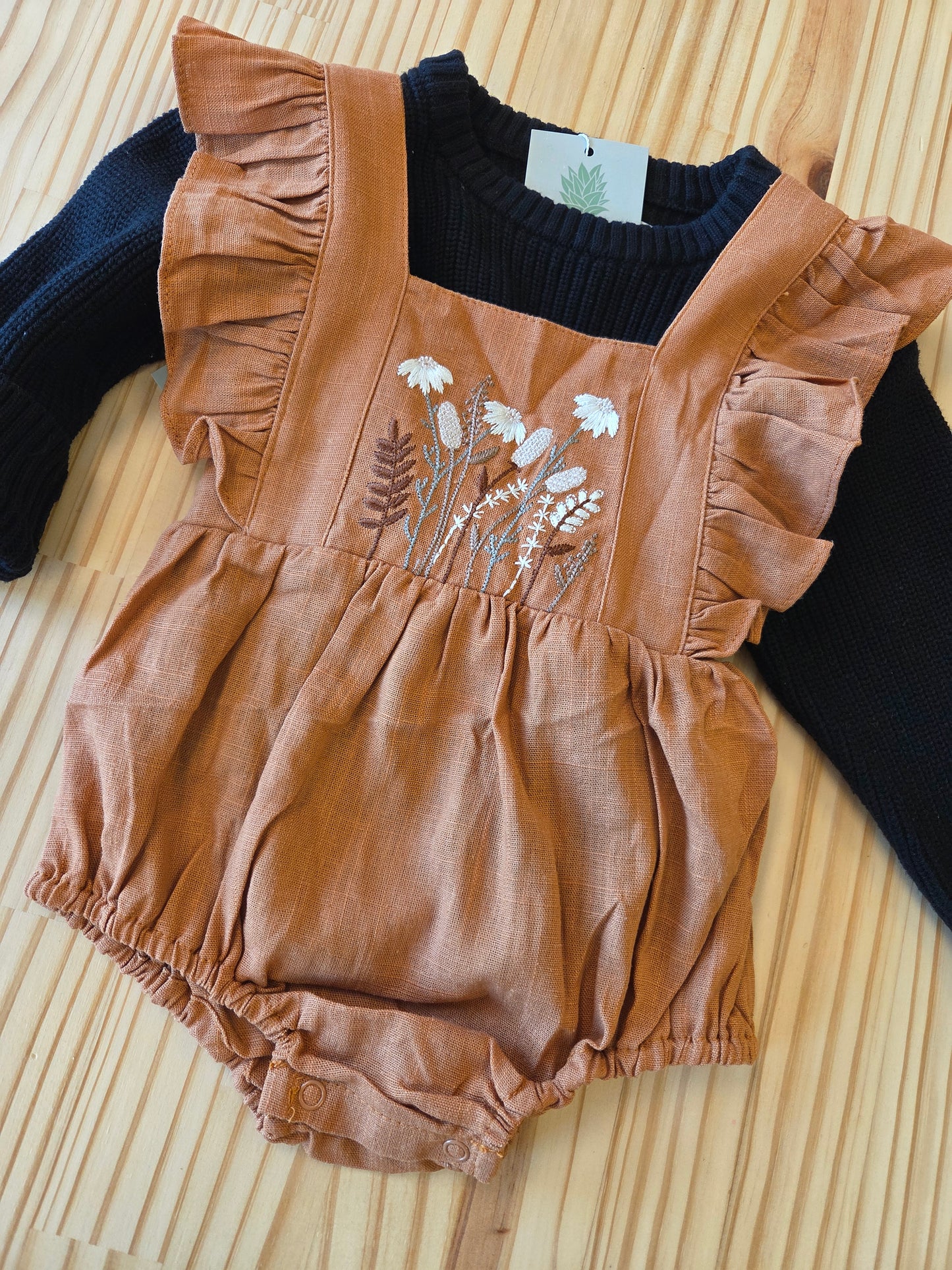 Close-up of Eleanor Embroidered Romper with sweater, showing linen texture, floral embroidery, and ruffle details