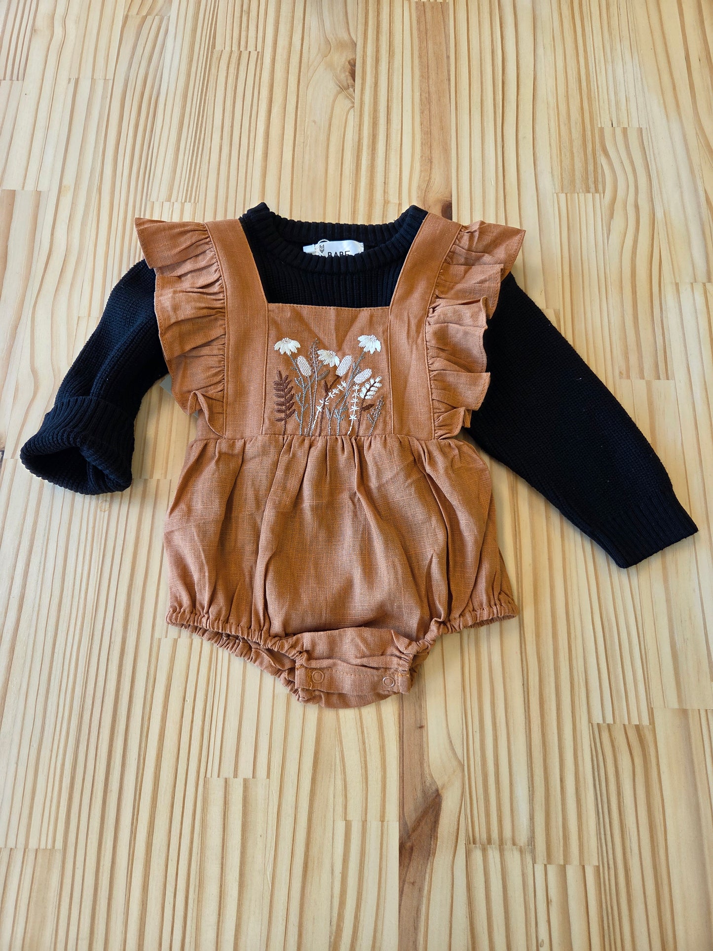 Eleanor Embroidered Romper styled with just a sweater, full outfit view, showing caramel linen, embroidery, and ruffle details