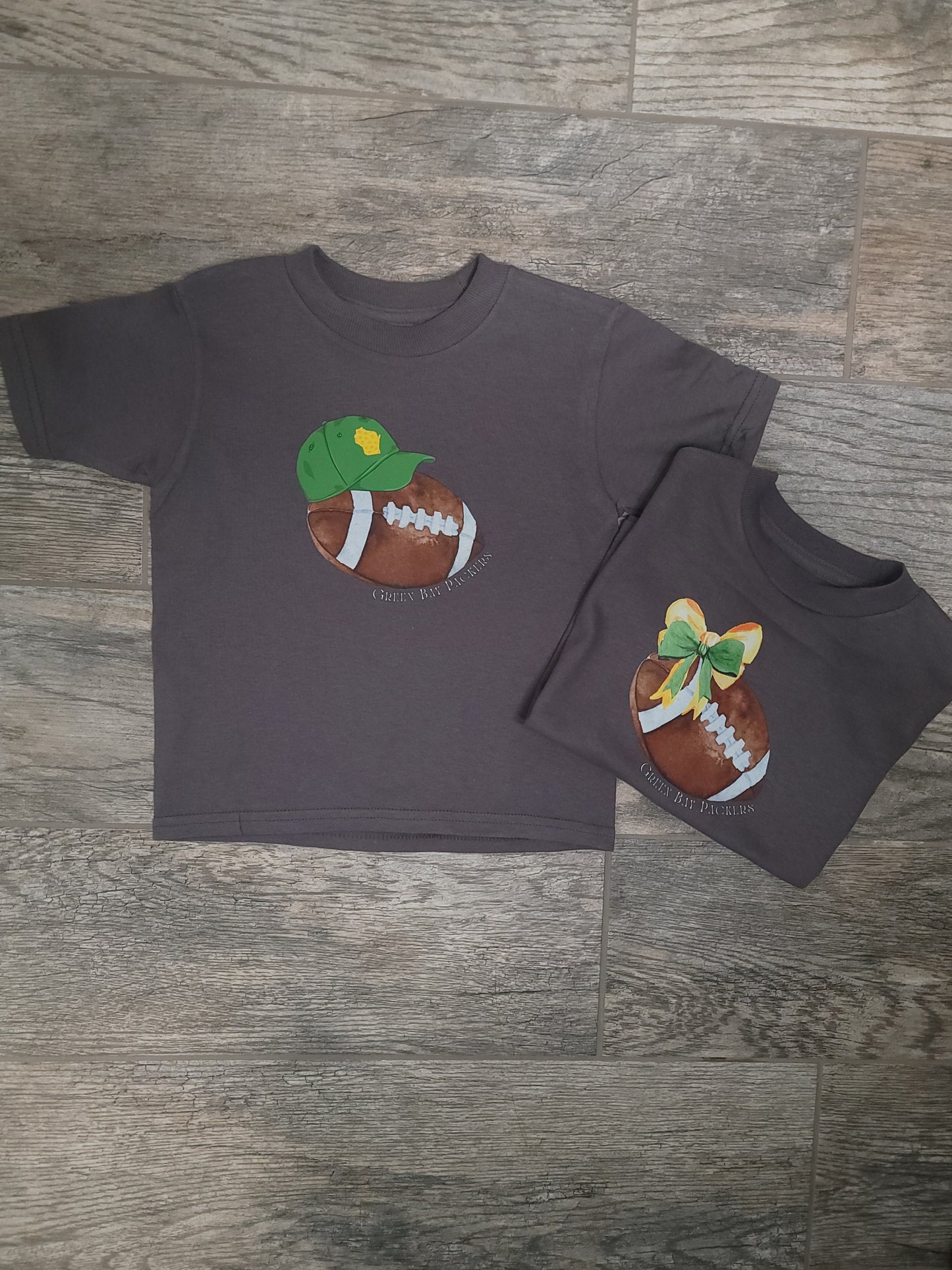 Flat lay of Green Bay Packers Toddler Tee with both styling options: bow or baseball cap, football accessory included