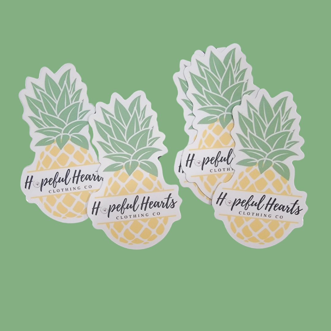 Flat lay of Hopeful Hearts pineapple emblem sticker, showing design, color, and size for laptop, water bottle, or notebook