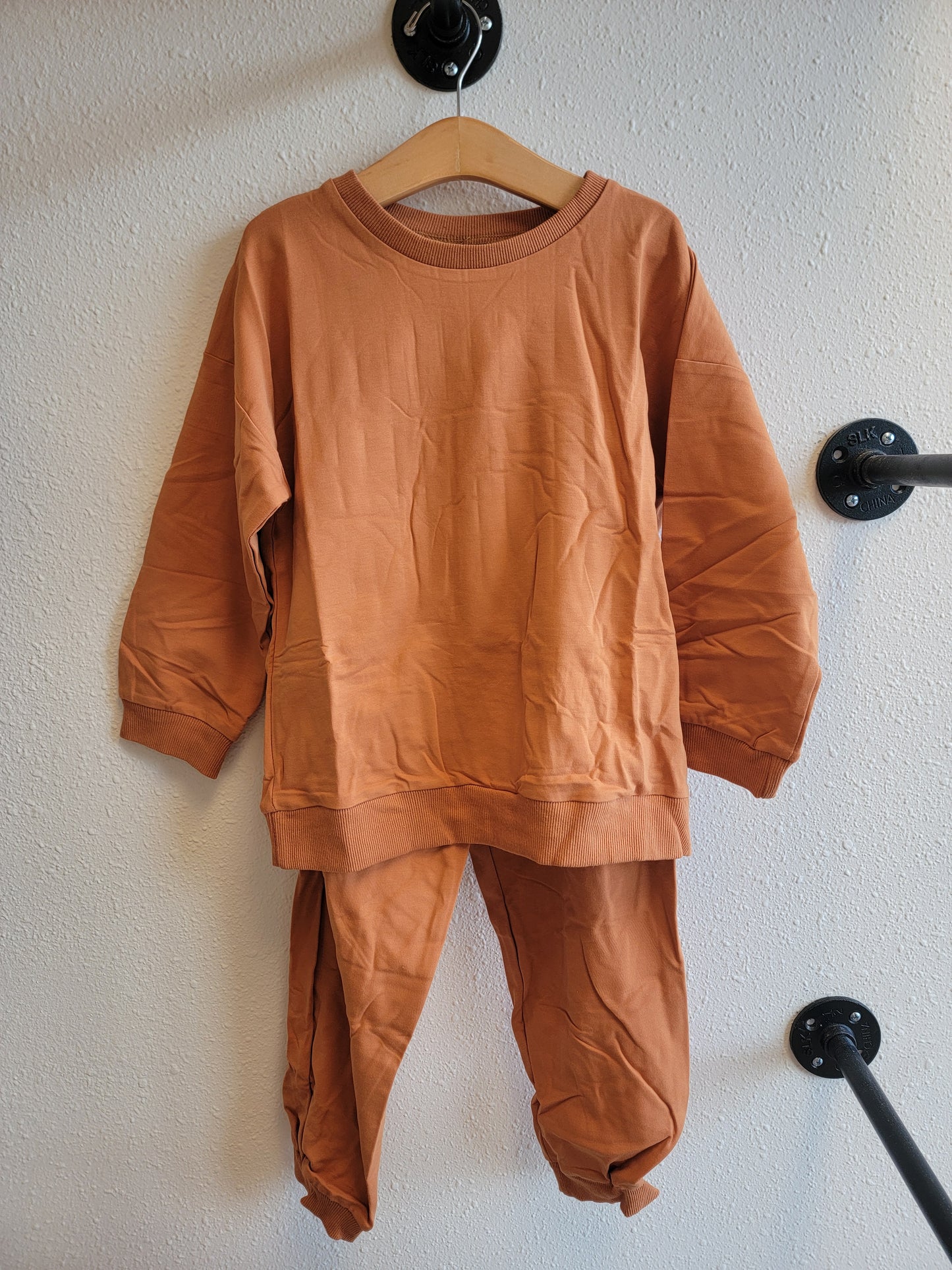 Front view of kids burnt orange sweat set hanging – matching sweatshirt and pants activewear outfit, size 8