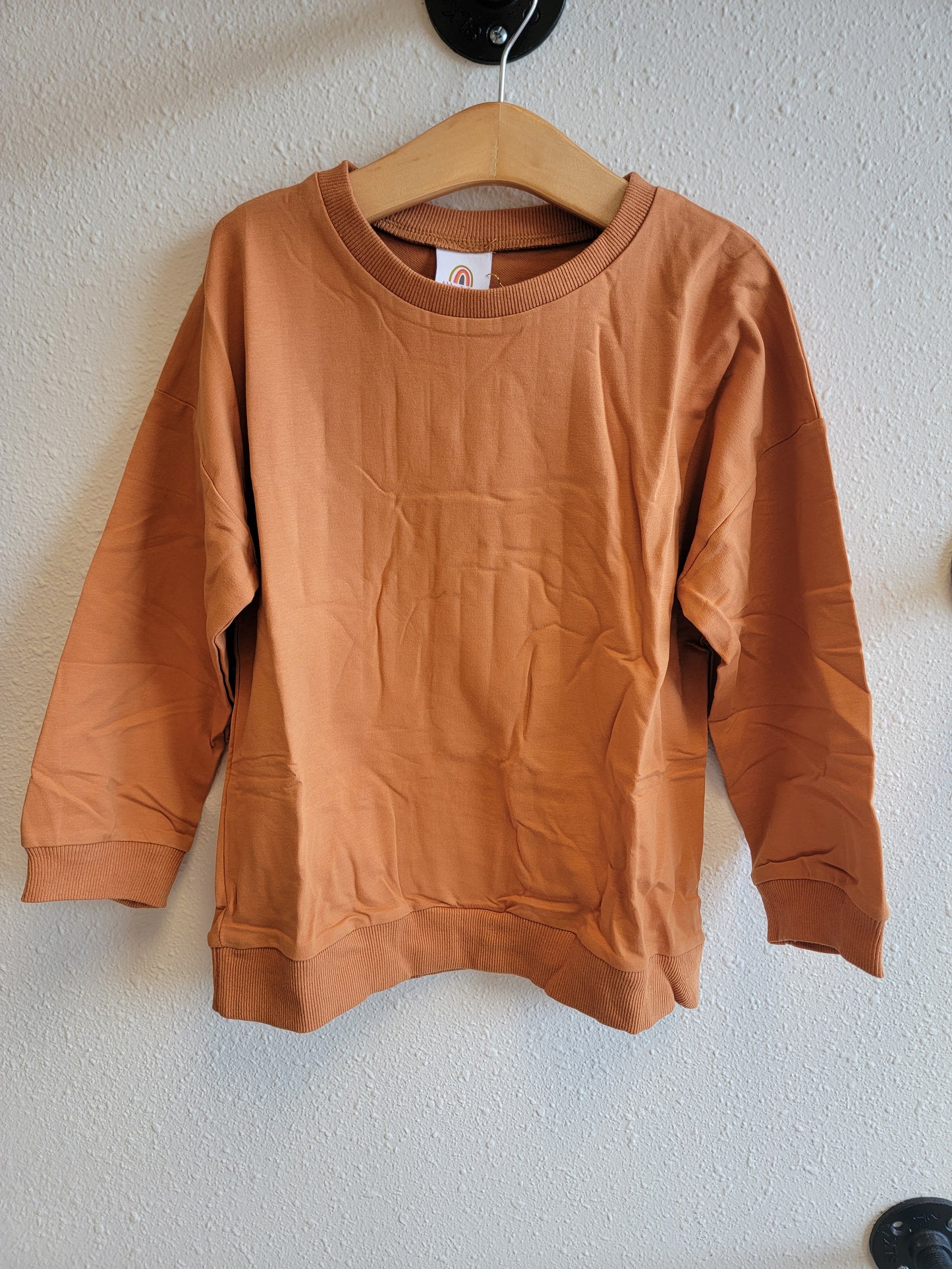 Front view of kids burnt orange sweatpants hanging – cozy and stylish youth bottoms, size 8