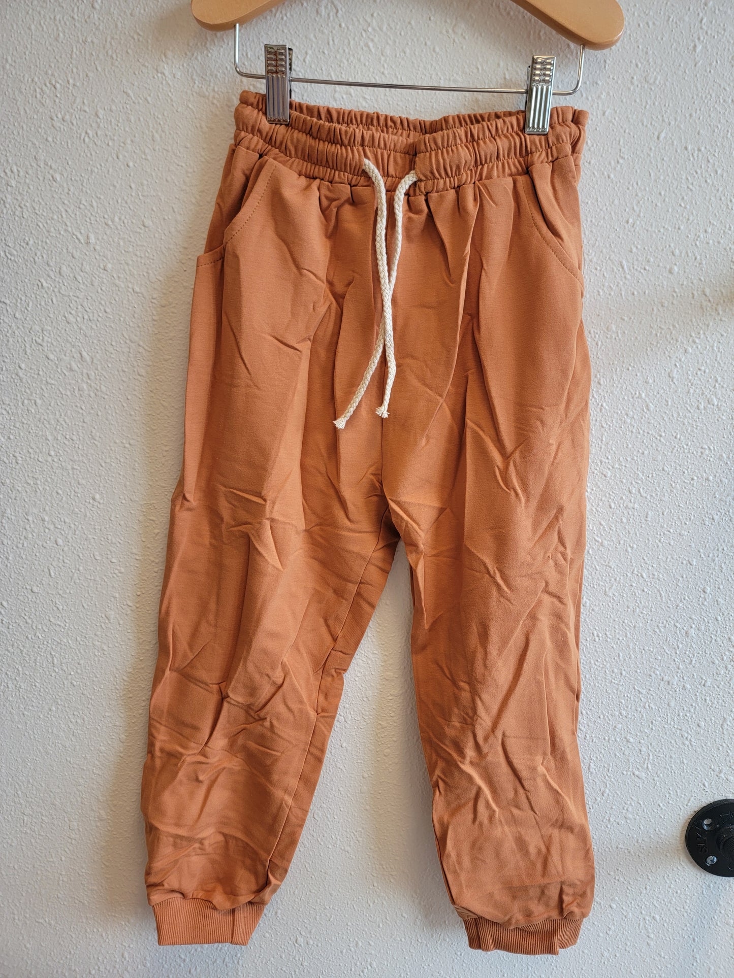 Front view of kids burnt orange sweatshirt hanging – stylish and comfortable youth top, size 8