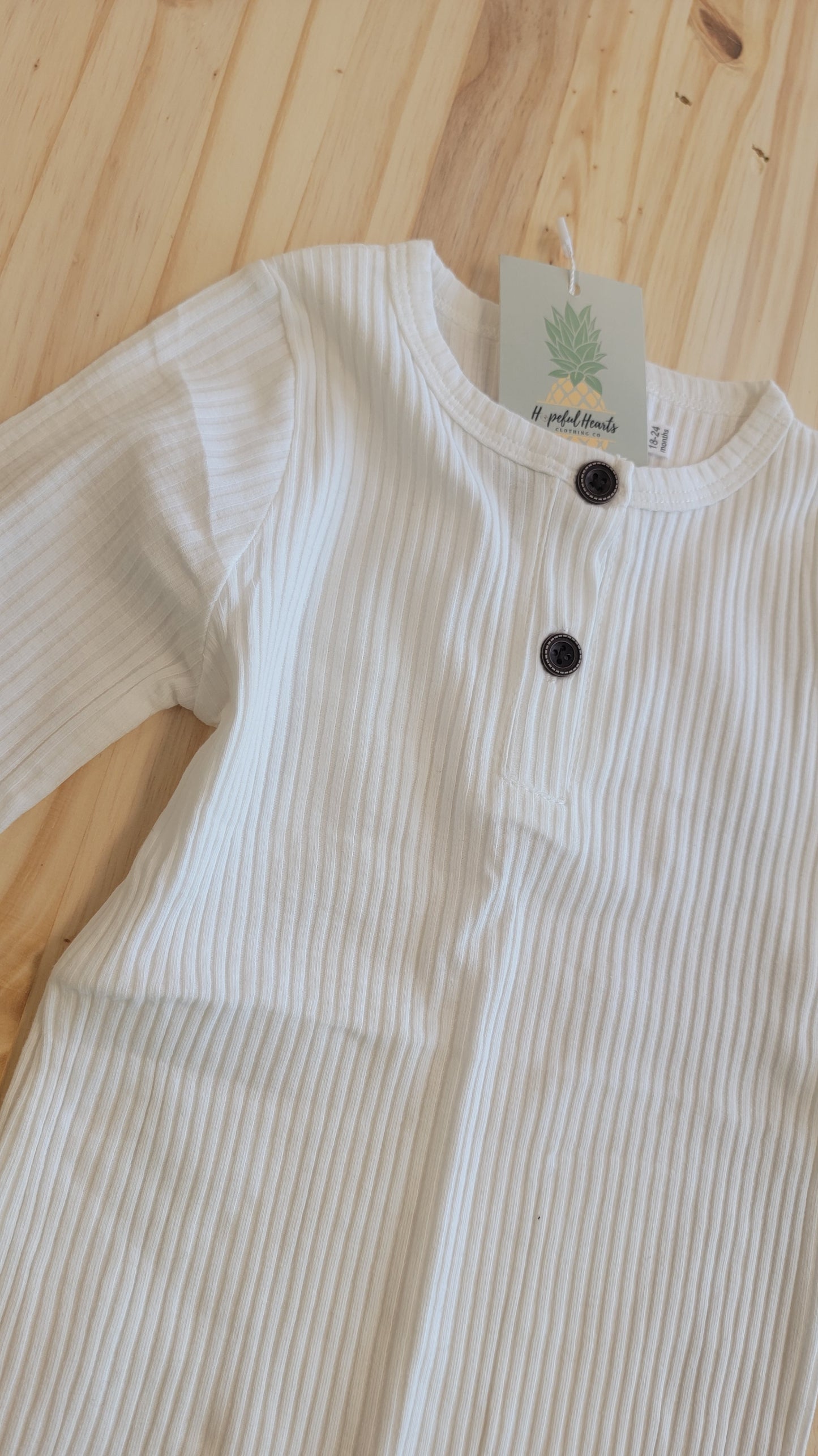 Close-up of ribbed cotton fabric on white baby romper – soft breathable material