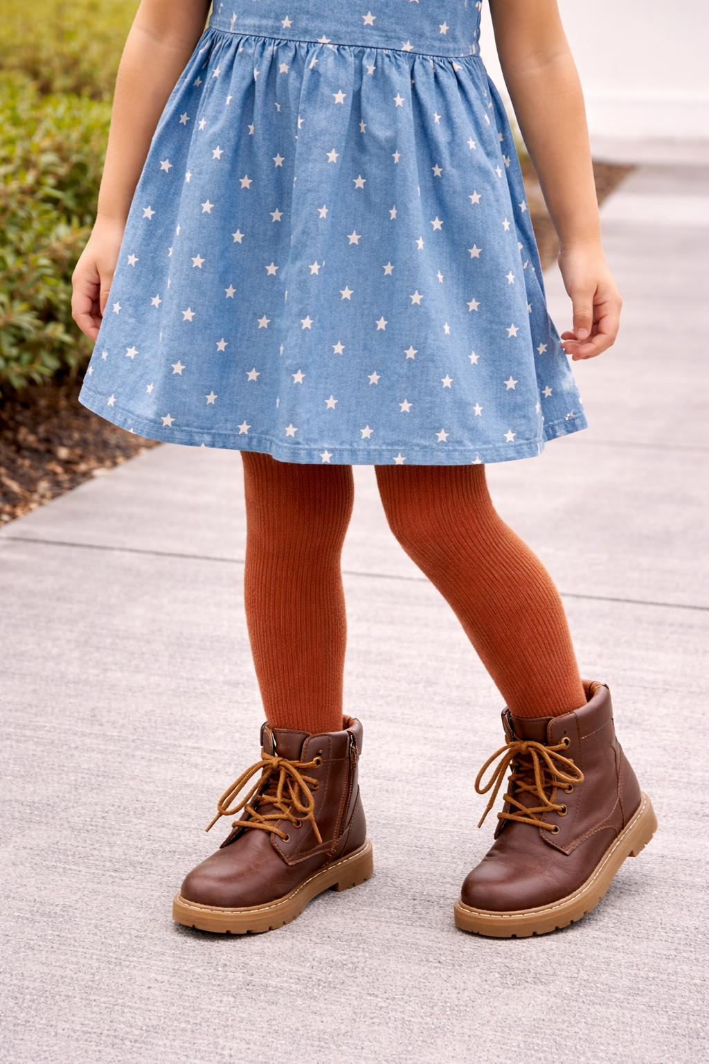 Youth size 8 girl wearing rust ribbed tights styled under a blue star-print dress, shown as a fall outfit pairing with lace-up boots.