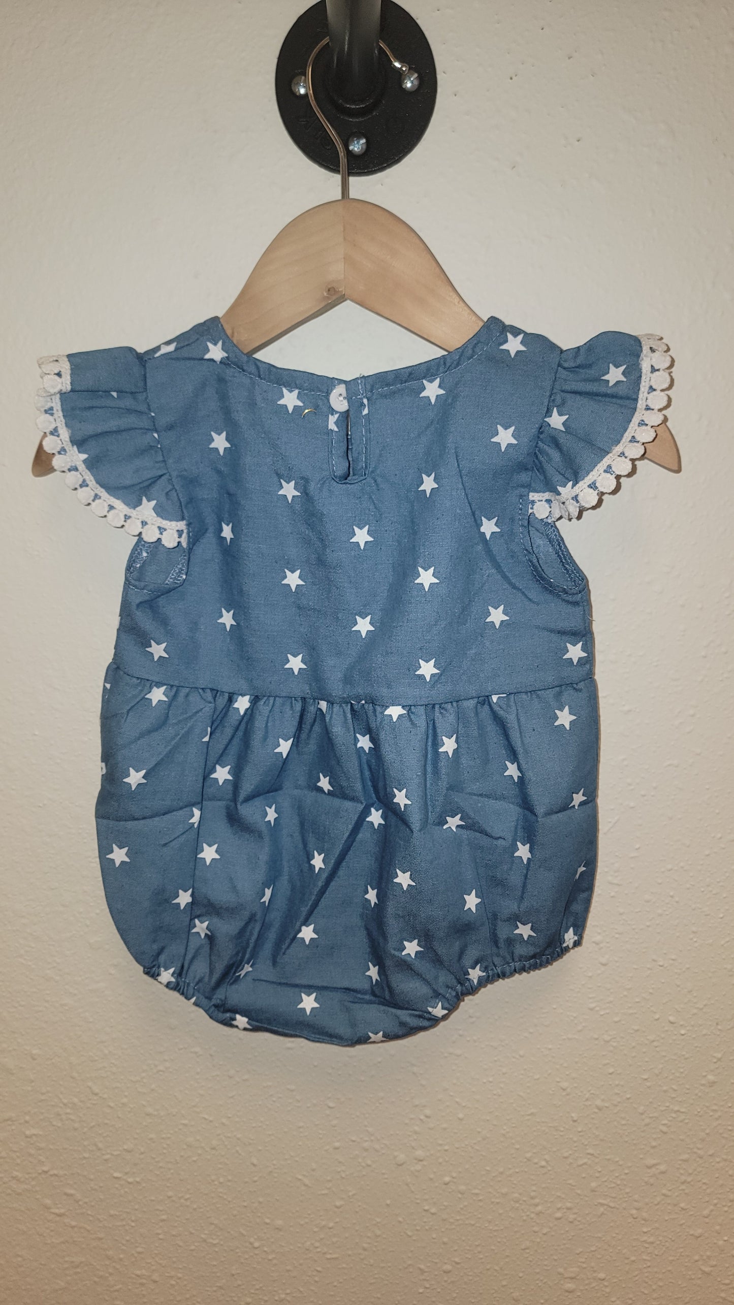 Back view of Stars Pom-Pom romper hanging – patriotic ruffle romper for baby girls and toddlers
