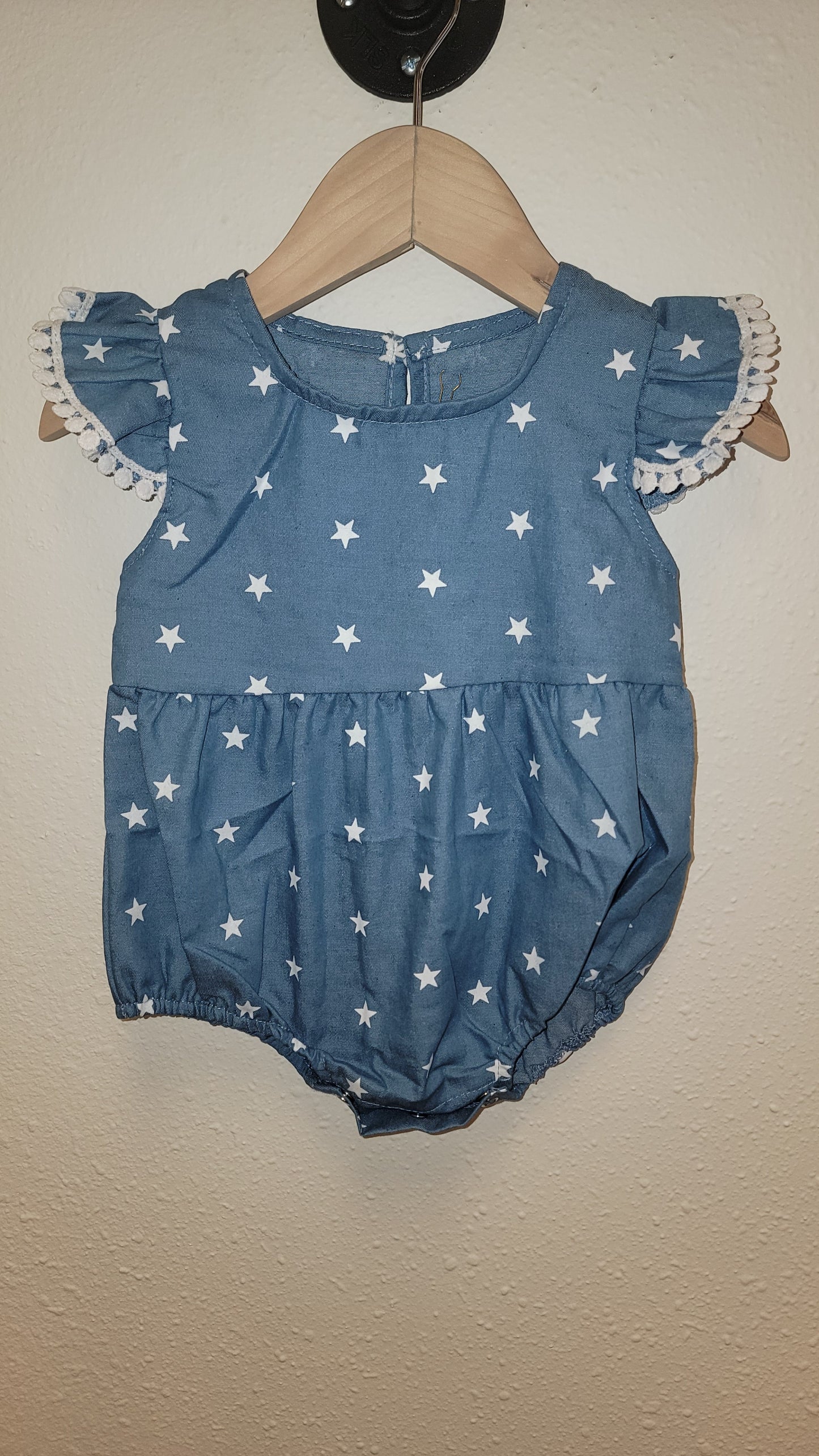 Front view of Stars Pom-Pom romper hanging – lightweight ruffle baby and toddler outfit for 4th of July celebrations