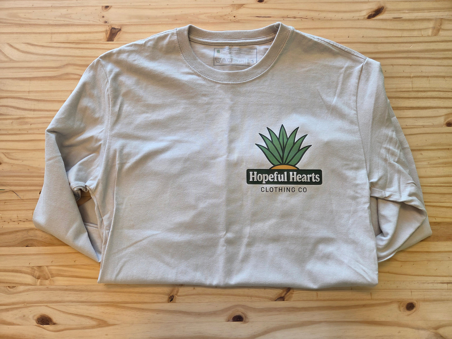 flat lay of Hopeful Hearts unisex long sleeve tee in dust color, front view showing “Hopeful Hearts Clothing Co.” logo