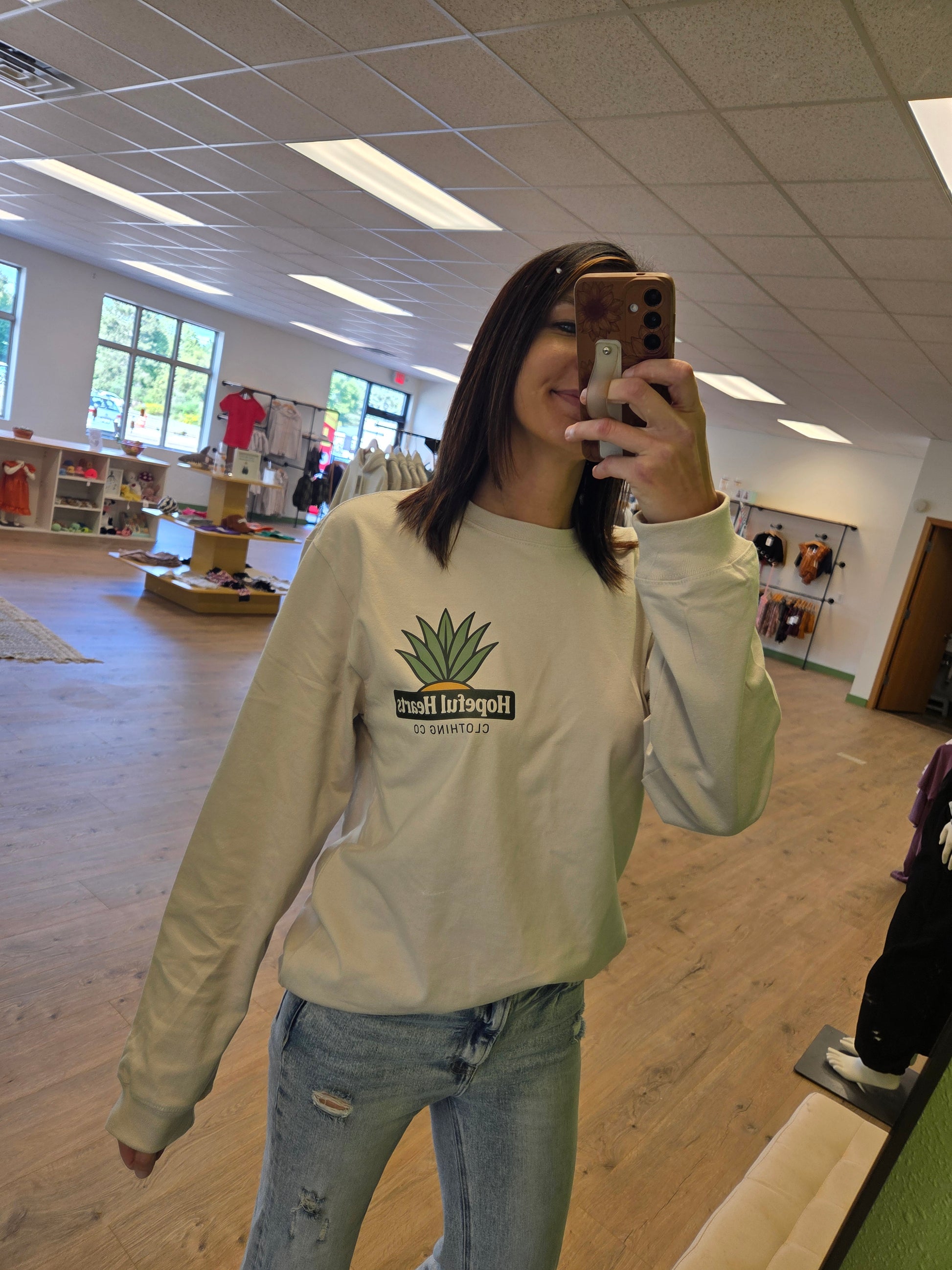 Woman wearing Hopeful Hearts unisex long sleeve tee in dust color, front view showing “Hopeful Hearts Clothing Co.” logo