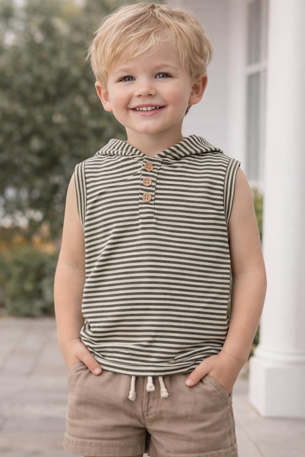 Toddler boy wearing sleeveless hooded striped top with wooden buttons, modeled on a 2–3 year old in a neutral outdoor setting