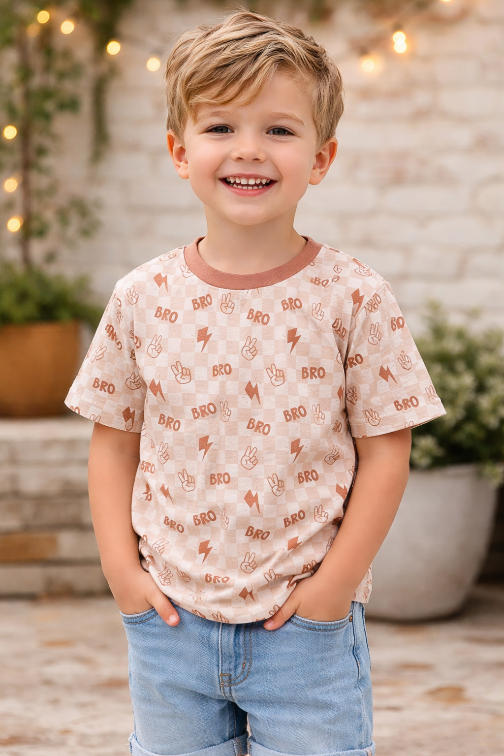 3T/4T toddler boy wearing beige and rust checkered “BRO” graphic tee with lightning bolt and peace sign print, styled with denim shorts outdoors