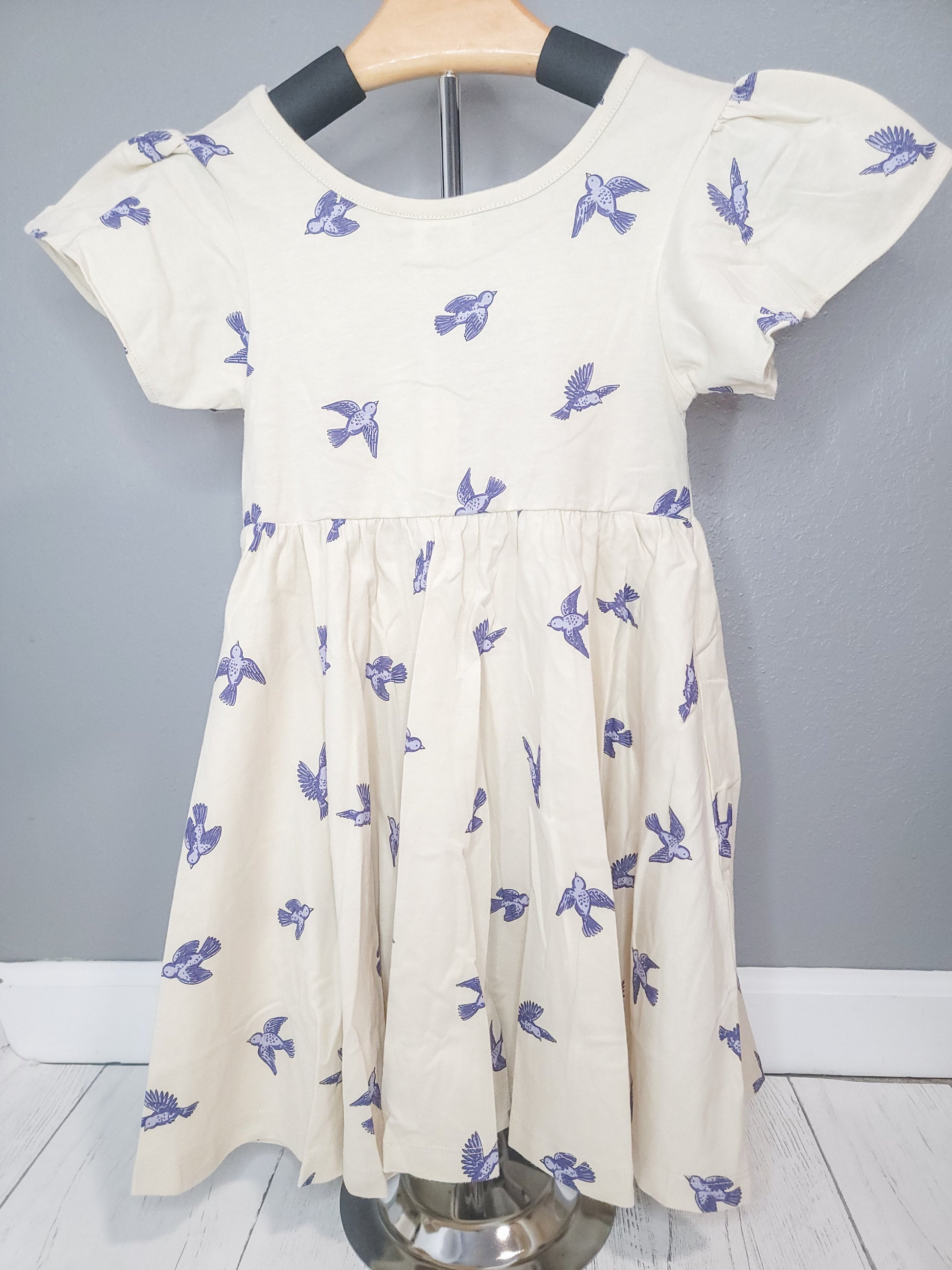 Bluebird Twirl Dress for toddler girls displayed on clothing rack, showing full cotton dress design and twirl-friendly fit