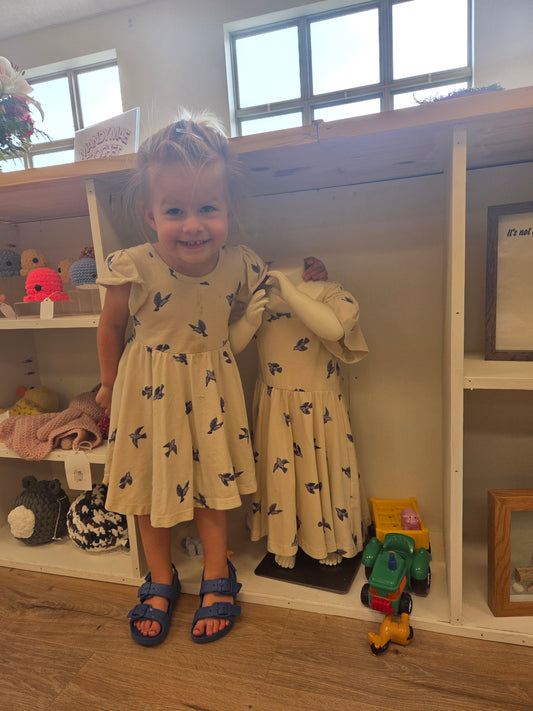 Toddler wearing Bluebird Twirl Dress standing next to mannequin, cotton toddler girls twirl dress, playful and comfortable