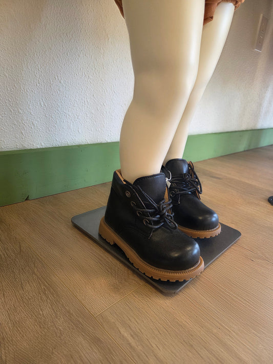 Side view of black unisex toddler and youth combat boots on mannequin, showing silhouette and lace-up detail