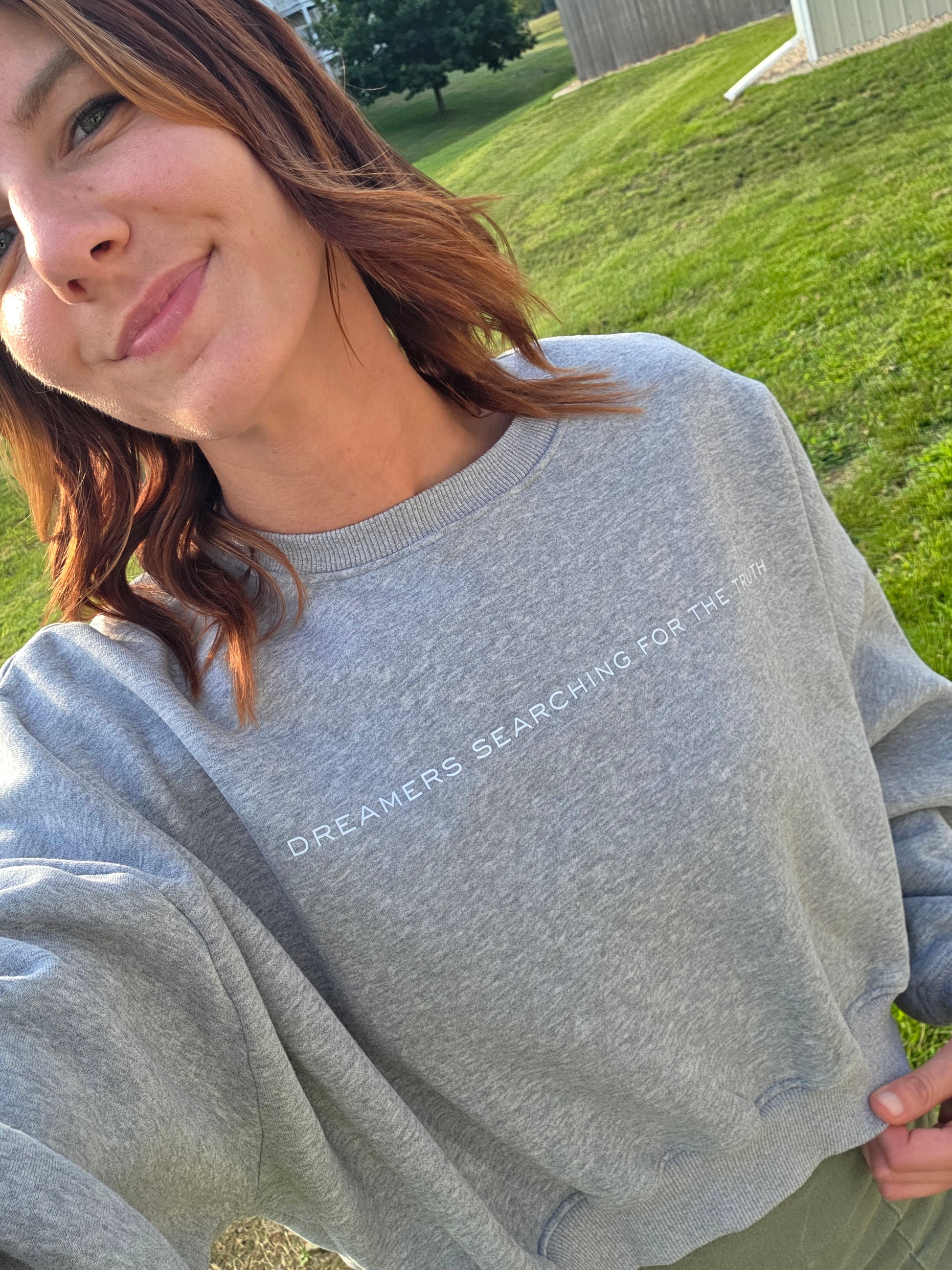 Close front view selfie of woman wearing Dreamers Searching for the Truth oversized crop crewneck, promoting infertility awareness