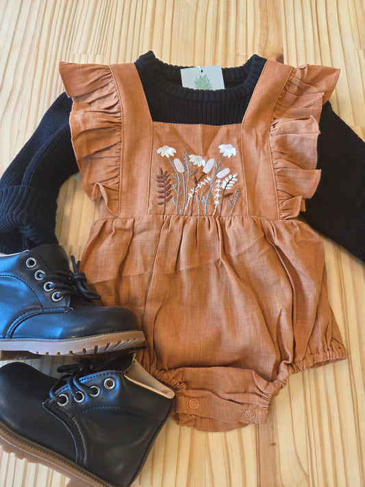 Close-up of Eleanor Embroidered Romper styled with sweater and boots, highlighting floral embroidery and ruffle details