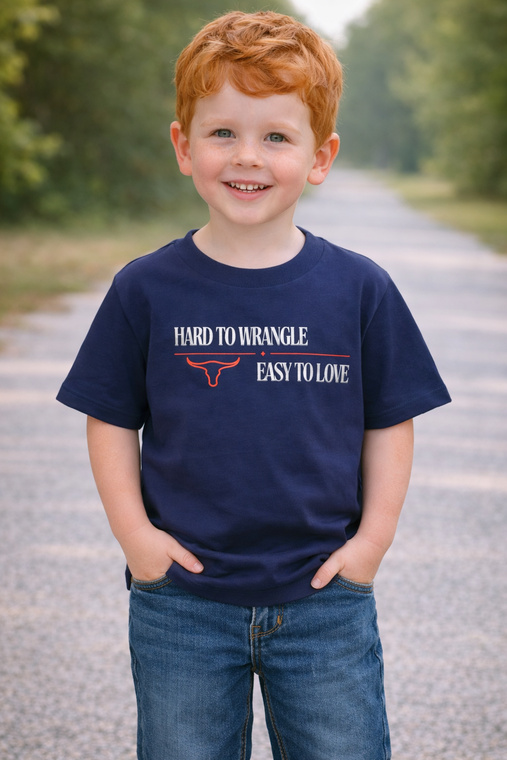 Red-haired toddler boy age 4 wearing a navy “Hard to Wrangle Easy to Love” graphic t-shirt