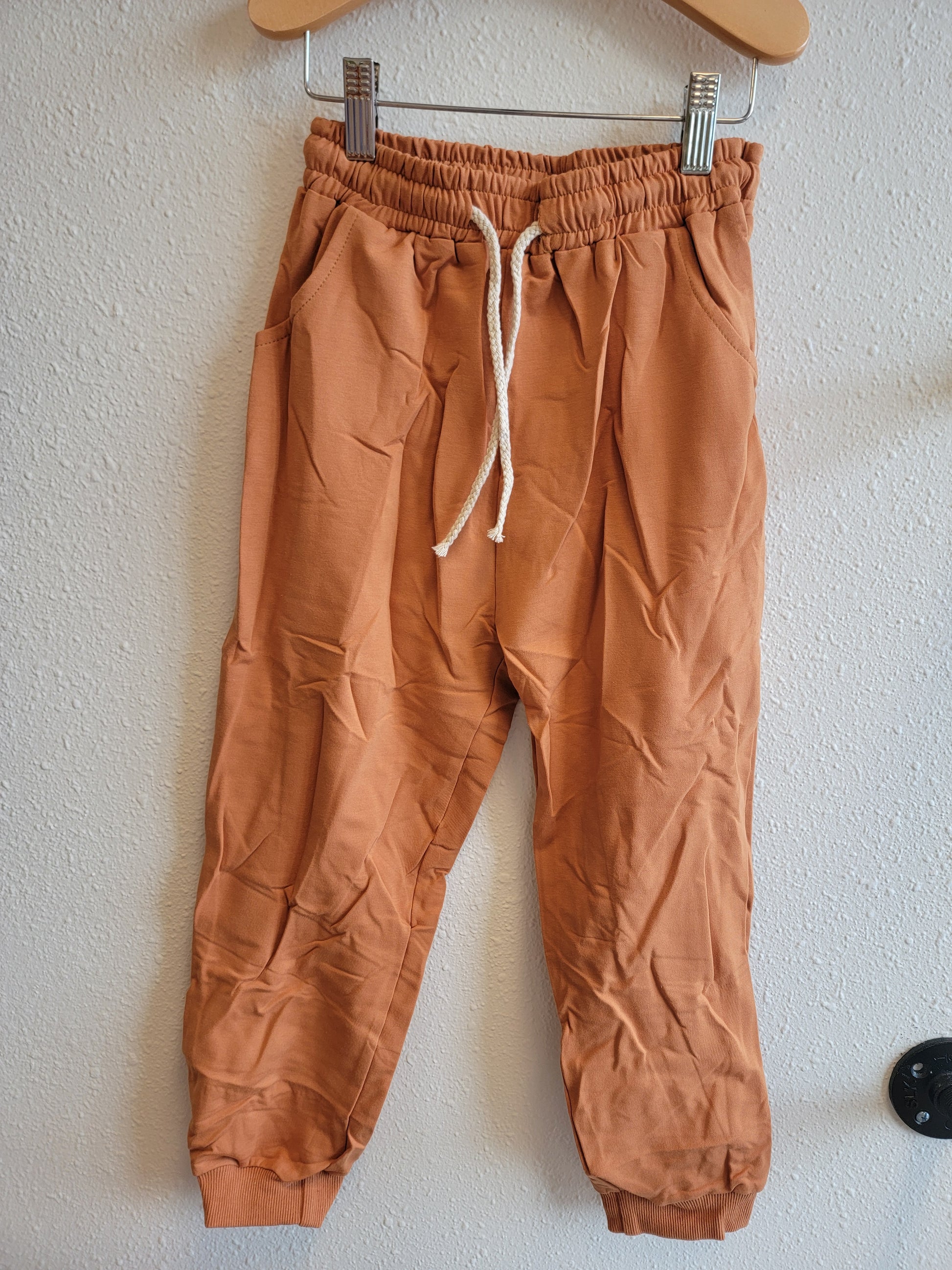 Front view of kids burnt orange sweatshirt hanging – stylish and comfortable youth top, size 8