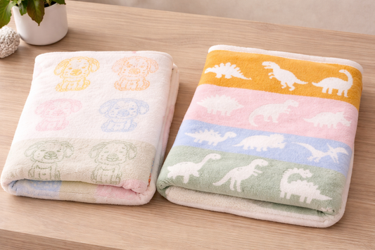 Two folded baby blankets side by side, featuring pastel puppy print and dinosaur print designs in 29 x 35 inch size