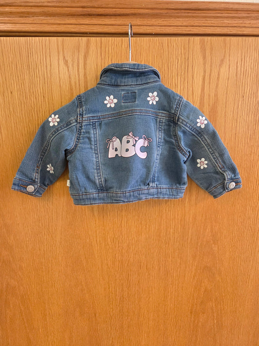 Baby girl jean jacket with pink and white floral patterns, pink ABC letters, and bow accents – playful boutique children’s clothing
