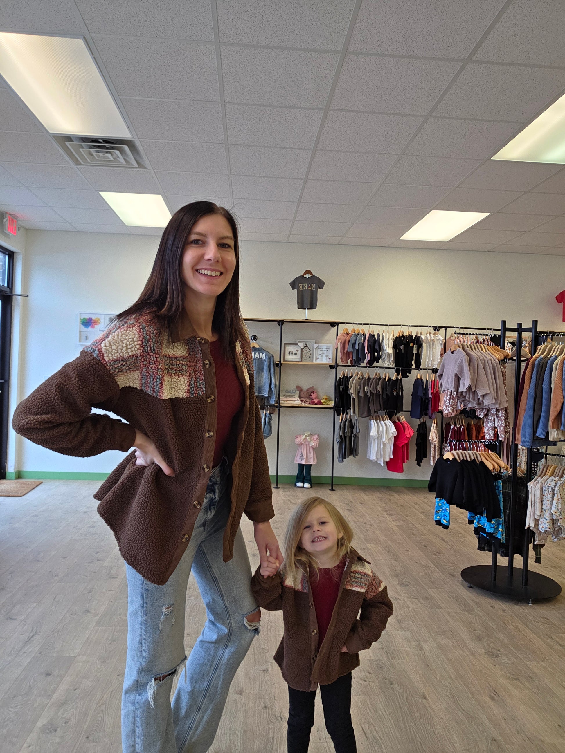 Two women standing in a store with clothing racks in the background