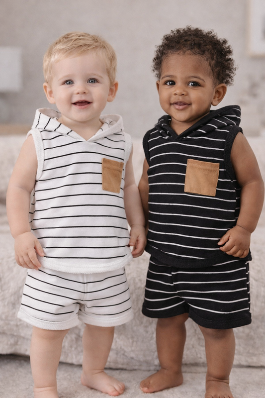 Two baby boys ages 6–18 months wearing sleeveless hooded striped outfits with tan pocket details, shown on models in a neutral indoor setting