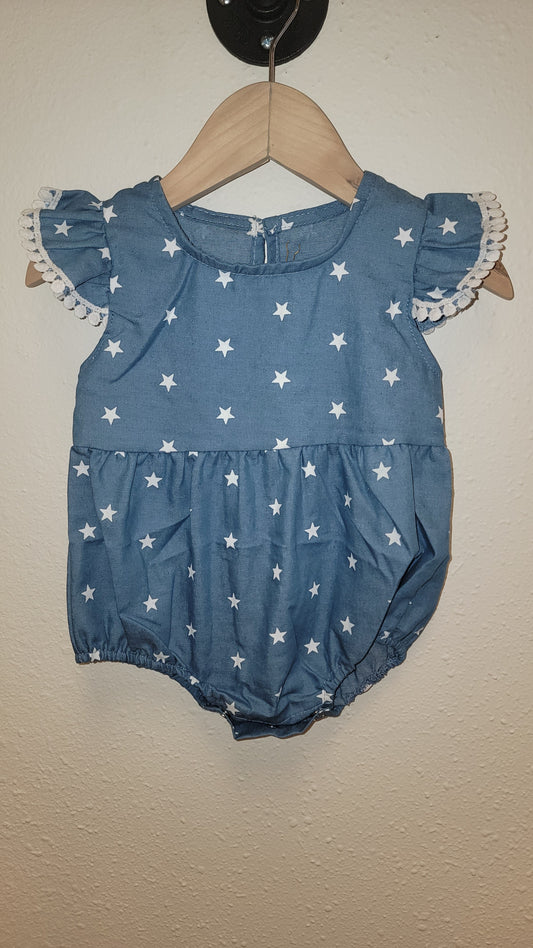 Front view of Stars Pom-Pom romper hanging – lightweight ruffle baby and toddler outfit for 4th of July celebrations