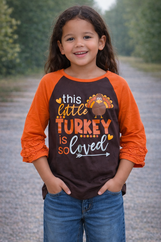 Girl model age 9–10 wearing a brown and orange “This Little Turkey Is So Loved” Thanksgiving shirt